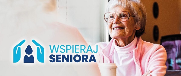 Na zdjęciu uśmiechnięta starsza pani w okularach, ubrana w różowy golf wpatrująca się w rozmytą postać. Po lewej stronie napis wspieraj seniora oraz logo z postacią  chronioną z obu stron dłońmi.